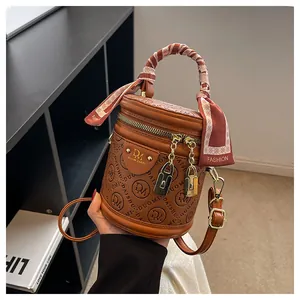 Brown cylinder handbag with a silk scarf handle and chain zipper details on PU leather
