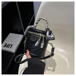 Detail der schwarzen Zylindertasche mit Seidentuch am Griff und goldenem Reißverschluss