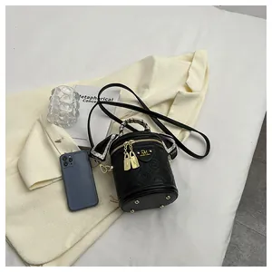 Detail of a black crocodile-embossed bucket bag with a patterned scarf and gold hardware