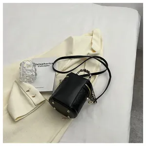 Detail view of black cylindrical handbag with embossed ring pattern and scarf handle