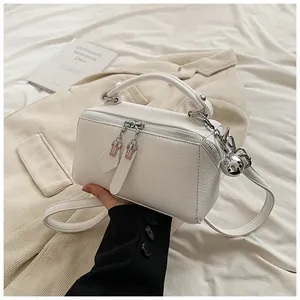 Detail of white litchi grain leather handbag with dual zippers and silver sphere charm