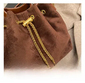 Detailed macro view of dark brown bucket bag with gold drawstring hardware and braided chain