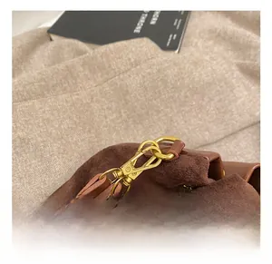 Detail of premium golden metal hook and chain on brown suede crossbody bucket bag