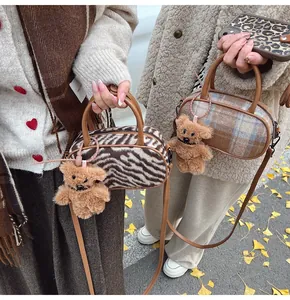 Détail du mini sac bowling à carreaux avec breloque ours en peluche et anses en cuir