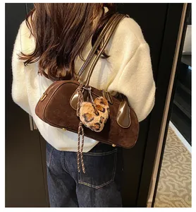 Close-up of matte dark brown suede bowling shoulder bag with leopard print heart charm