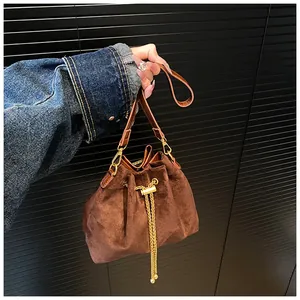 Detailed view of brown drawstring bucket bag with gold chain and matte texture finish