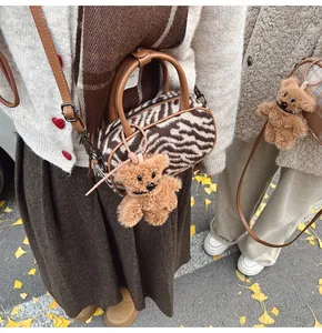Détail du sac bowling à motif zèbre avec breloque ours en peluche sur fond d'automne
