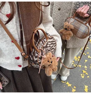Détail du sac bowling en maille à carreaux avec breloque ours et anses en cuir
