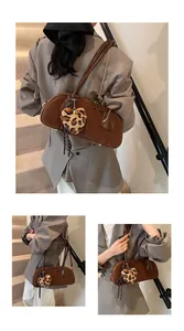 Detail of brown vintage suede shoulder bag with leopard heart charm and leather trim