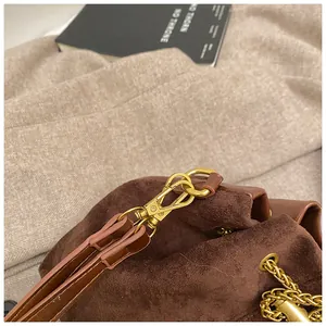 Detailed close-up of dark brown suede and smooth leather texture with gold metal hook