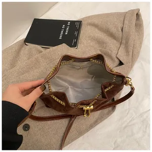 Macro view of retro brown bucket bag showing interior pocket and gold chain closure