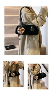 Detail of matte black shoulder bag with leopard heart charm and gold hardware accents