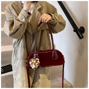 Detail of burgundy suede shoulder bag with leopard heart charm and detachable strap