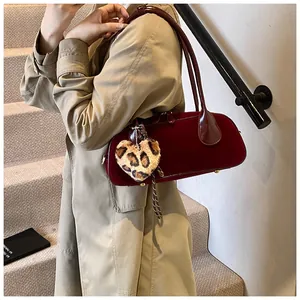 Detail of vintage burgundy bowling bag with leopard heart charm worn over a camel coat