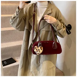 Detail of burgundy velvet bowling bag with leopard heart charm and gold hardware