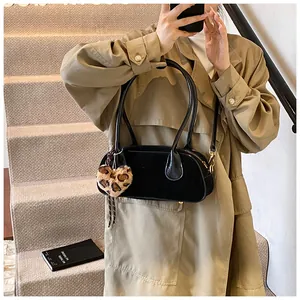 Detailed view of black retro underarm bag with leopard heart charm on model