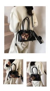 Détail d'un sac à main plissé noir avec breloque cœur léopard et bandoulière amovible