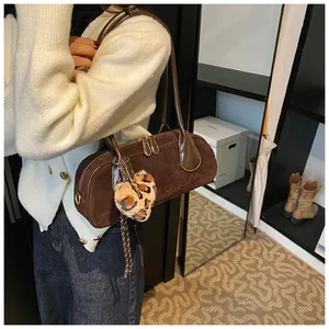 Detail of dark brown suede bowling bag with leopard heart charm and thin shoulder straps