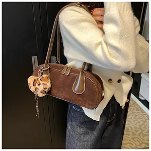 Detail view of a retro brown frosted suede Boston bag with a leopard print fur ball charm