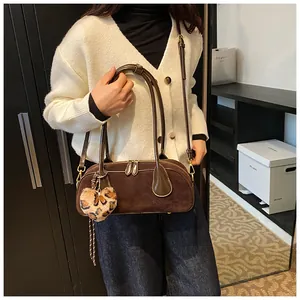 Detail showing deep brown matte suede shoulder bag with heart leopard print charm