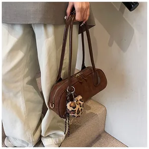 Detail of dark brown matte suede shoulder bag with dual zippers and leopard heart charm