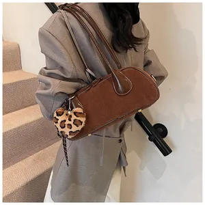 Detail of vintage brown suede shoulder bag with leopard heart charm and leather strap