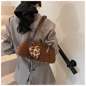Retro brown suede shoulder bag with leopard heart charm worn with a grey blazer