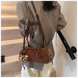 Detail of a brown suede underarm bag with leopard heart charm and stylish double straps