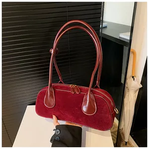 Detail of burgundy matte suede underarm bag with smooth leather straps and gold zippers