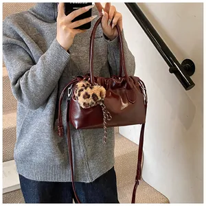 Détail du sac à main bordeaux froncé avec cuir brillant et breloque coeur léopard peluche