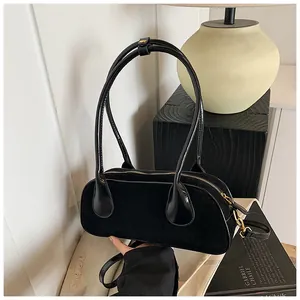 Detail view of black suede and leather bowling bag with gold hardware and shoulder strap
