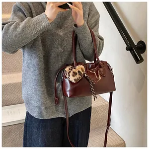 Détail du sac à main bordeaux verni avec breloque cœur léopard et bandoulière fine