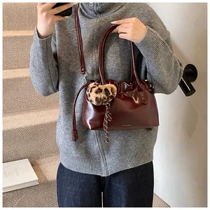 Détail du sac en cuir verni bordeaux avec plis et breloque cœur en peluche léopard