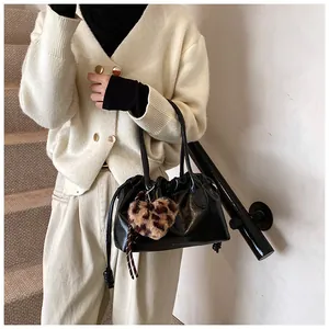 Détail du sac à main plissé noir avec breloque cœur léopard porté par un mannequin