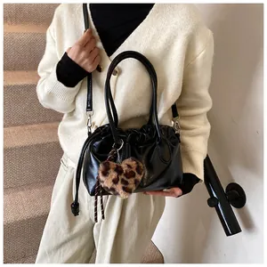 Détail du sac à main noir plissé en cuir PU avec breloque cœur léopard porté par un mannequin