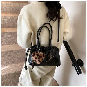 Détail d'un sac à main noir plissé brillant avec breloque cœur léopard et bandoulière