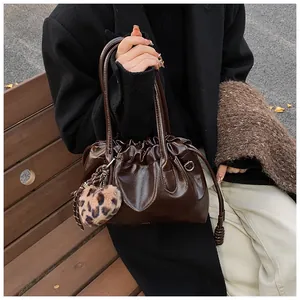 Détail du sac à main en cuir marron foncé avec cordon plissé et pompon léopard chic