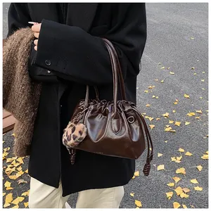 Détail du sac à main plissé marron foncé avec fini brillant et breloque pompon léopard