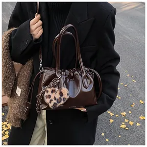 Détail du sac à main plissé marron foncé avec cordon et breloque cœur imprimé léopard