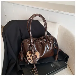Détail d'un sac cabas plissé marron foncé avec pendentif cœur léopard sur costume noir