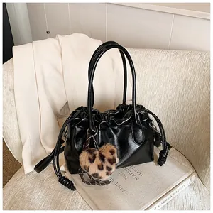 Détail du sac plissé noir en cuir brillant avec un charmant pendentif cœur léopard