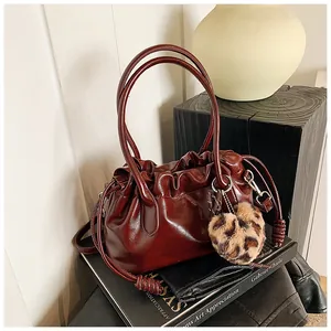 Détail du sac à main plissé bordeaux avec cordon de serrage et breloque cœur léopard
