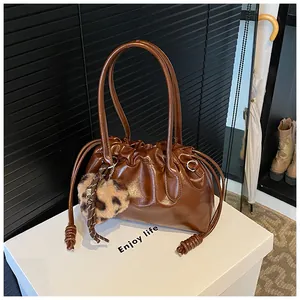 Sac à main marron plissé en cuir verni avec un charme de cœur léopard sur bloc blanc