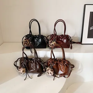 Sacs à main plissés vintage en noir, rouge et marron avec breloques léopard sur support blanc