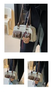 Detail of cream canvas and brown leather shoulder bag with vintage pocket and bear charm