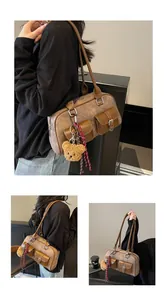 Detail of vintage brown shoulder bag showing multi-pocket design and cute bear pendant