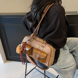 Vintage brown shoulder pillow bag with dual front pockets and plush bear charm on straps