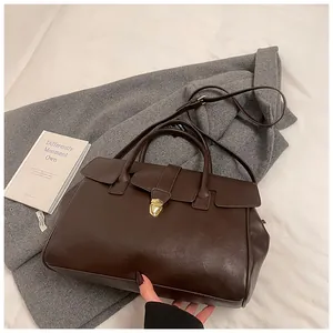 Detalle de bolso tote vintage de piel marrón con hebilla metálica dorada de cierre