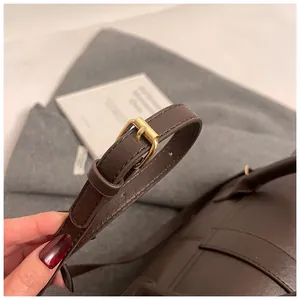 Detalle de correa ajustable de cuero marrón oscuro con hebilla metálica dorada