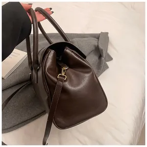 Detalle del bolso Boston café oscuro en cuero sintético liso con herrajes dorados y asa